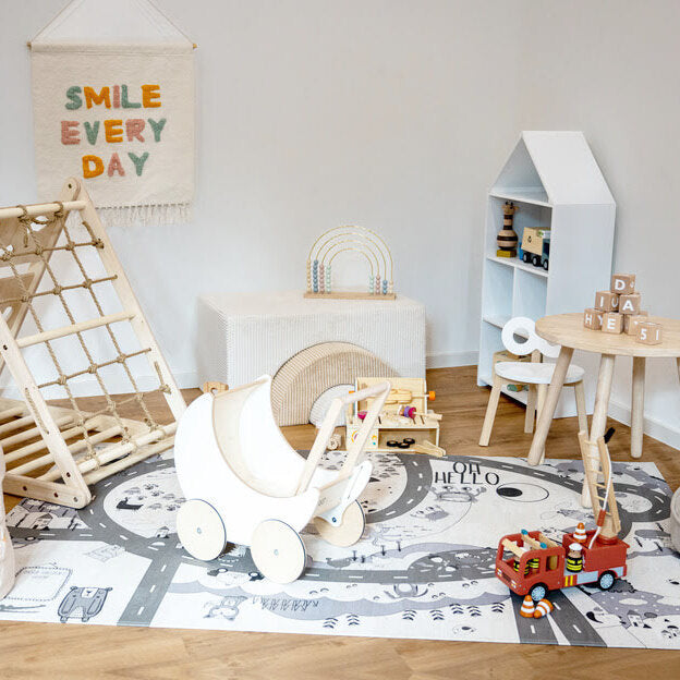 Kinderecke auf Kork Teppich mit Kletterdreieck, Sitzsack, Puppenwagen aus Holz und weiteren Holzspielsachen in weiß beige