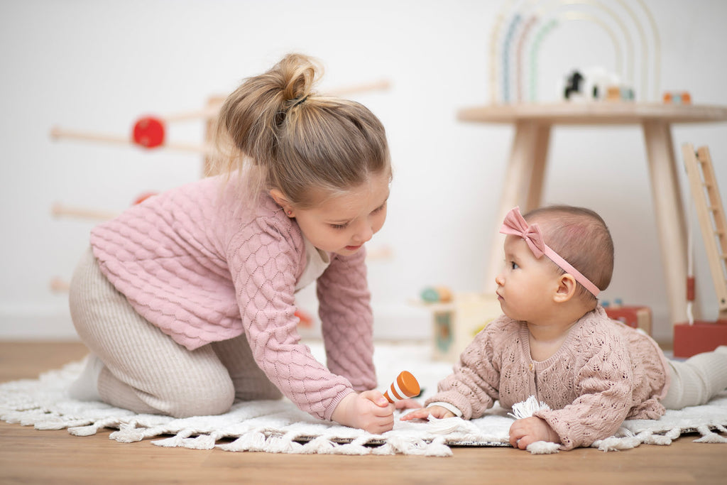 Kleinkind und Baby spielen in Kinderecke auf Teppich