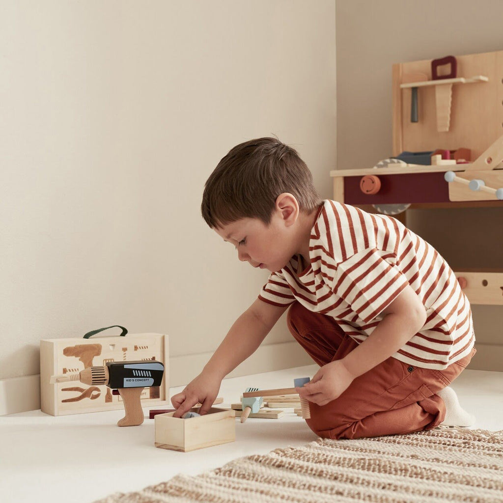 Kind auf Boden vor Werkzeug aus Holz