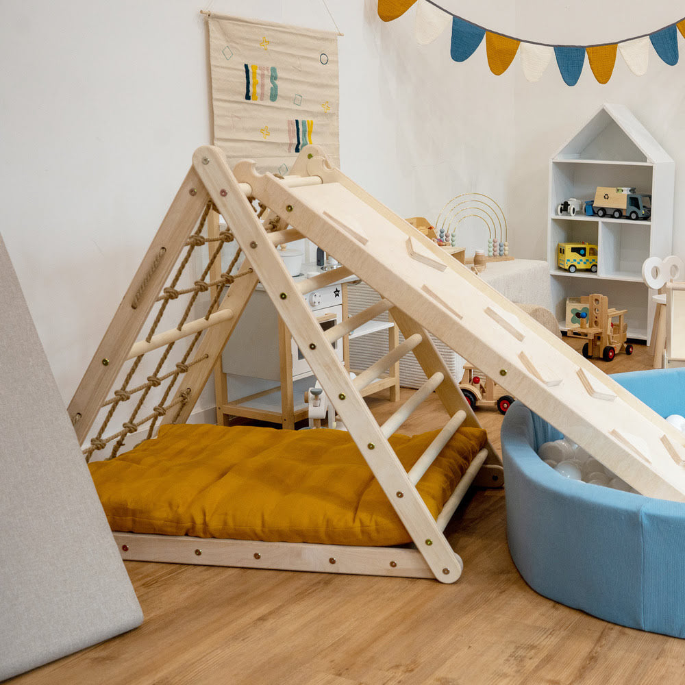 Kinderzimmer mit Kletterdreieck, Rutsche in ein blaues Bällebad und blaues Tipi Zelt mit Sitzsack, Girlanden und diversen Holzspielsachen