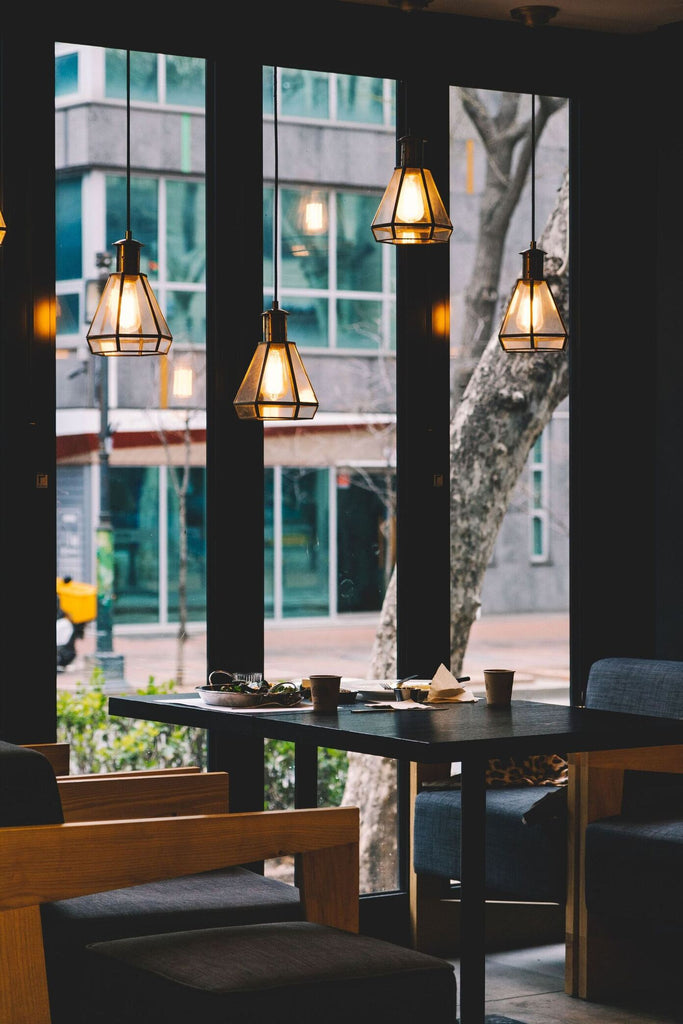 Restaurant Café von Innen mit dunkler Möblierung und hängenden Pendelleuchten vor tiefer Fensterfront