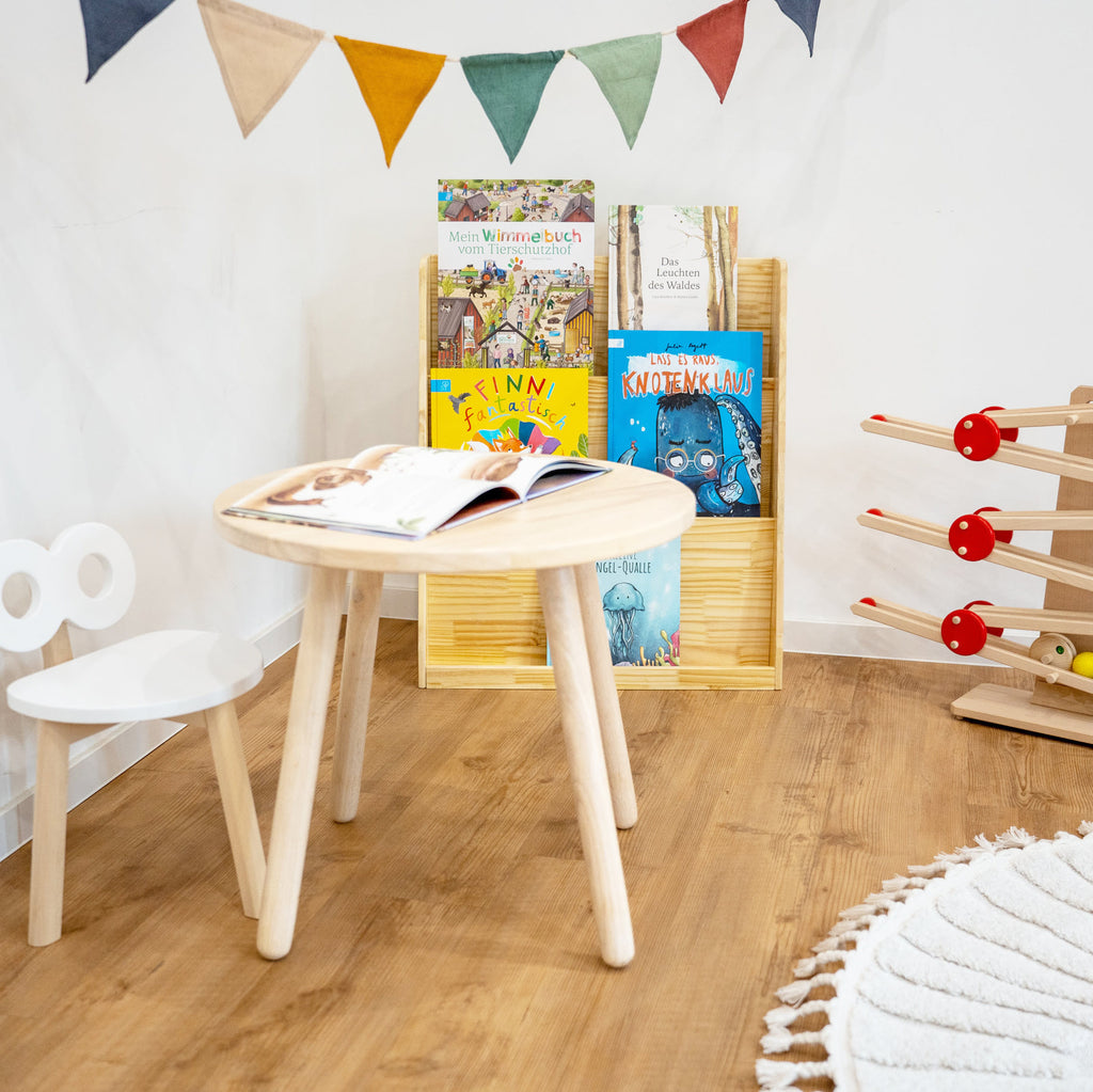 Bücherecke mit rundem Kindertisch und Stuhl aus Holz, einer Kugelbahn und Bücherregal aus Holz mit Kinderbüchern