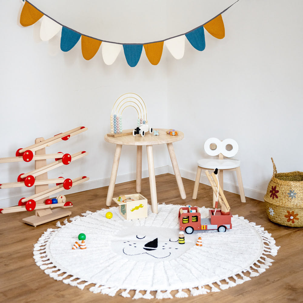 Kinderecke mit Kugelbahn, Kindertisch und Stuhl aus Holz und Löwenteppich in beige, Spielzeuge aus Holz auf dem Boden und Tisch