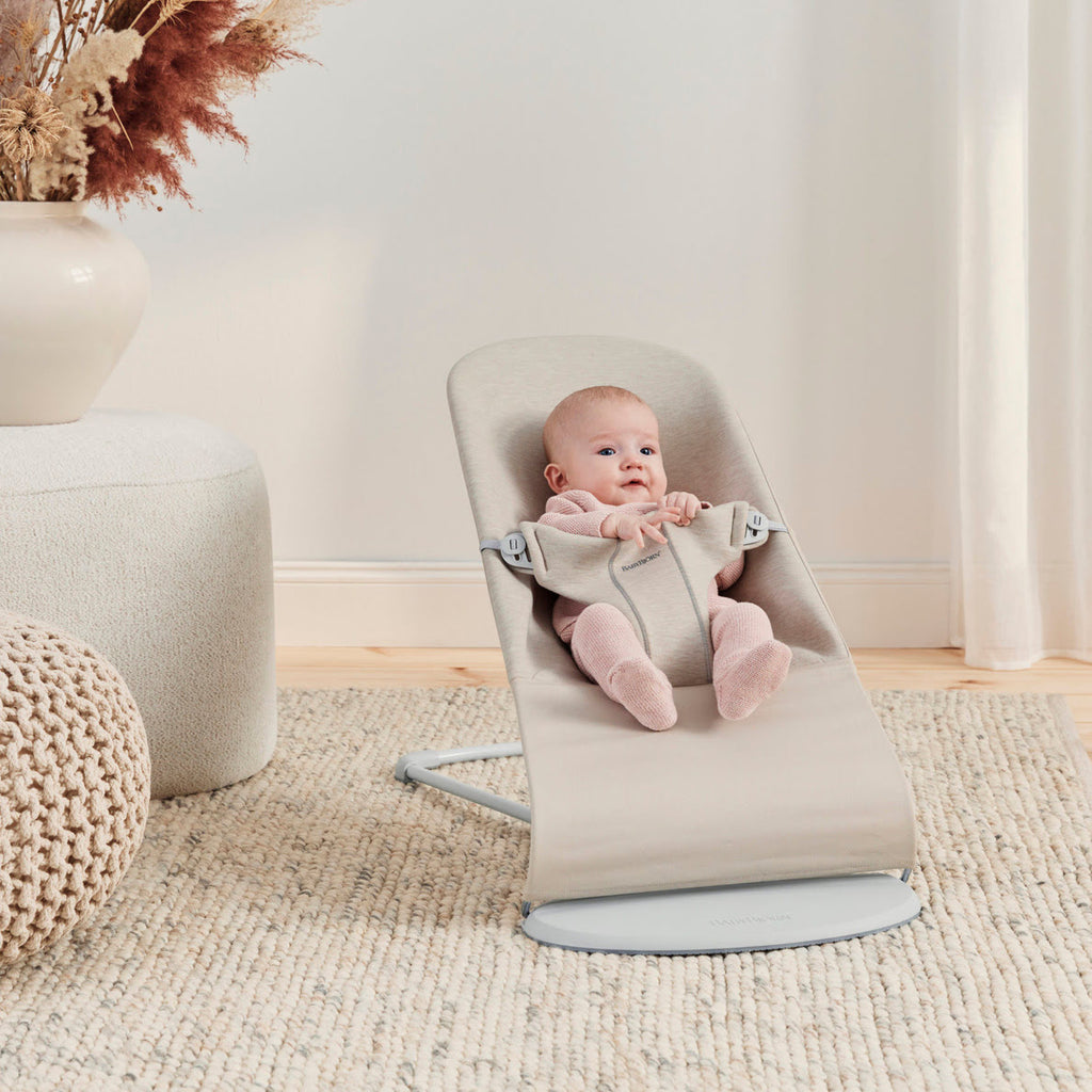 Babywippe beige mit Baby auf Teppich