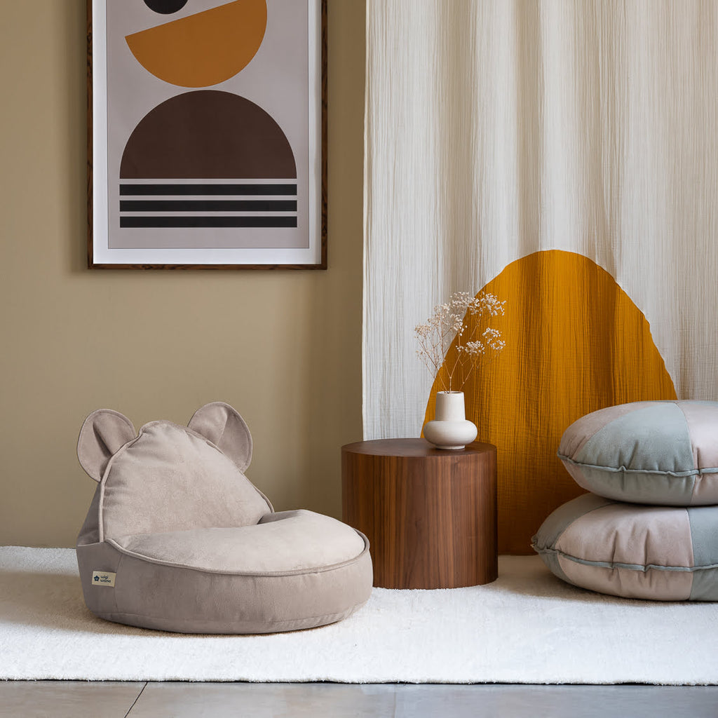 Sitzsack mit Bärenohren Samt beige auf Teppich mit Beistelltisch und Vase und zwei Sitzkissen mint grün vor Gardine Gelb weiß
