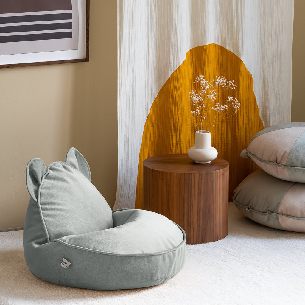 Sitzsack mit Bärenohren Samt mint grün und Beistelltisch Holz mit Vase auf Teppich und zwei Sitzkissen mint grün gestapelt