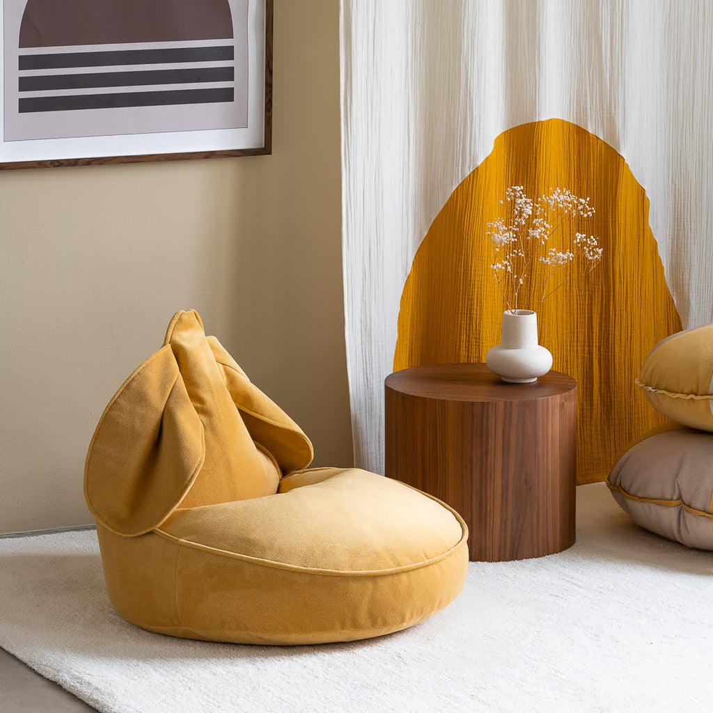 Sitzsack mit Hasenohren Samt gelb vor Beistelltisch Holz mit Vase auf Teppich beige