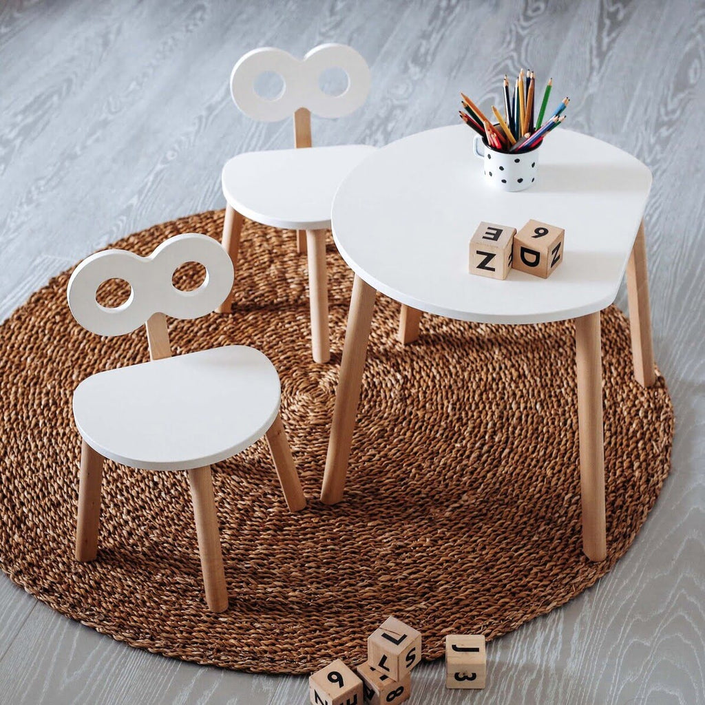 Kindertisch aus Holz halbmondform in weiß und Kinderstühle auf Teppich
