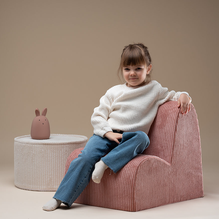 Kind auf Kindersessel aus Breitcord rosa und Sitzpouf weiß
